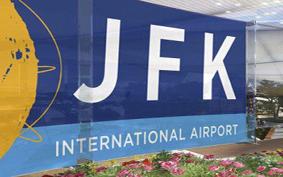 A sign for jfk international airport with flowers in front of it.