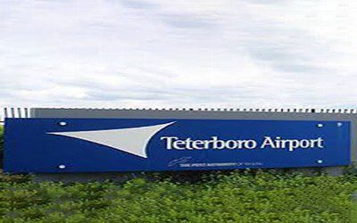 A sign for teterboro airport in the grass.