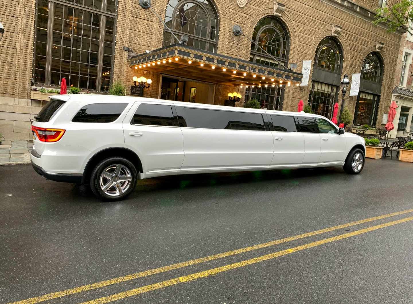 A white limo is driving down the street.