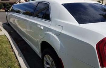 A white limo parked on the side of a road.