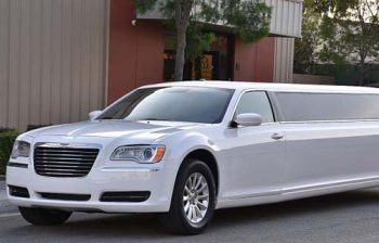 A white limo parked in front of a building.